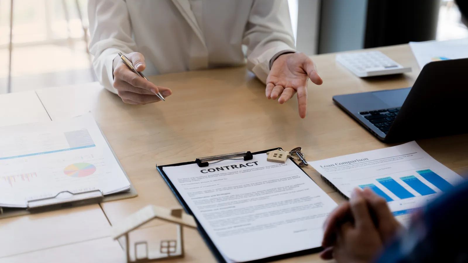 Mesa de despacho con un contrato de financiación, gráficos y calculadora