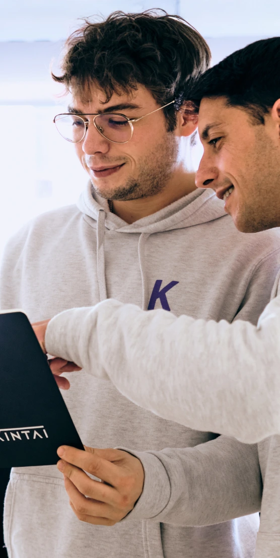 Dos compañeros de Kintai conversando junto a una mesa de trabajo